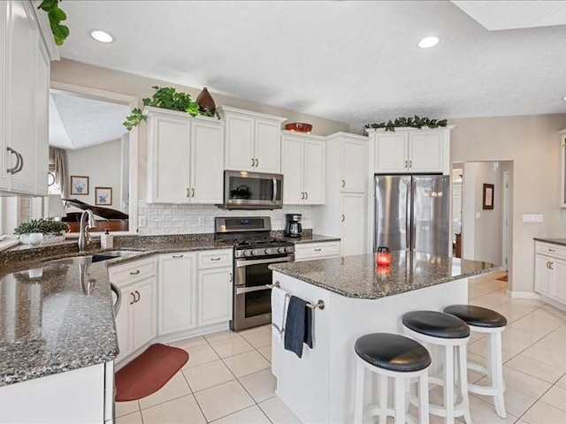 kitchen featuring white cabinetry, appliances with stainless steel finishes, sink, and dark stone counters