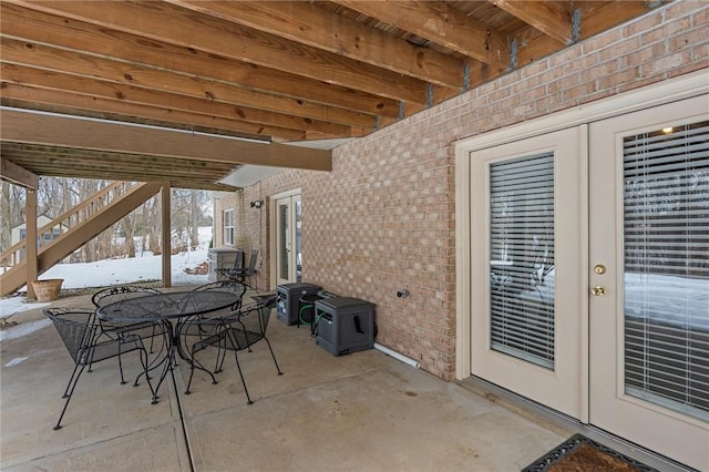 snow covered patio featuring french doors