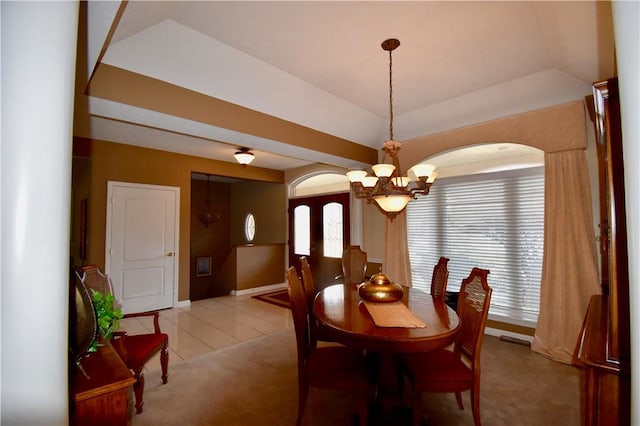 dining room with an inviting chandelier, a raised ceiling, and light tile patterned floors