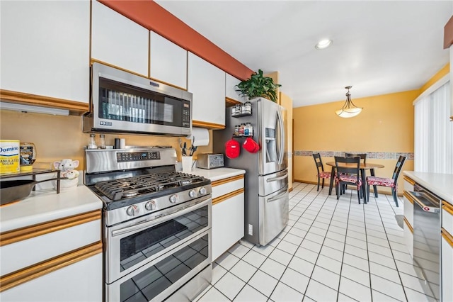 kitchen featuring stainless steel appliances, white cabinetry, light tile patterned flooring, and decorative light fixtures