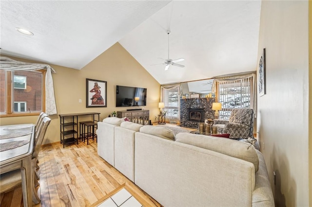 living room with ceiling fan, high vaulted ceiling, and light hardwood / wood-style floors