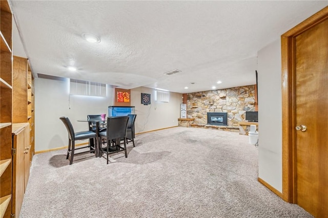 dining room featuring a fireplace, carpet floors, and a textured ceiling