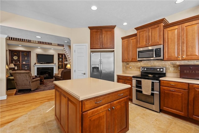 kitchen with stainless steel appliances, a center island, light wood-type flooring, and backsplash