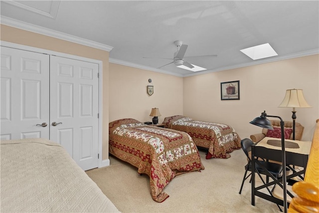 bedroom featuring crown molding, a skylight, a closet, ceiling fan, and carpet