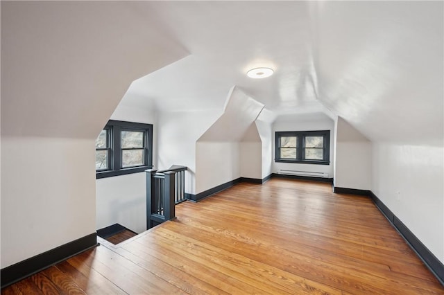 additional living space with lofted ceiling, wood-type flooring, and a baseboard radiator