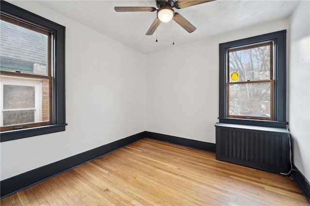 empty room with radiator, light hardwood / wood-style flooring, and ceiling fan