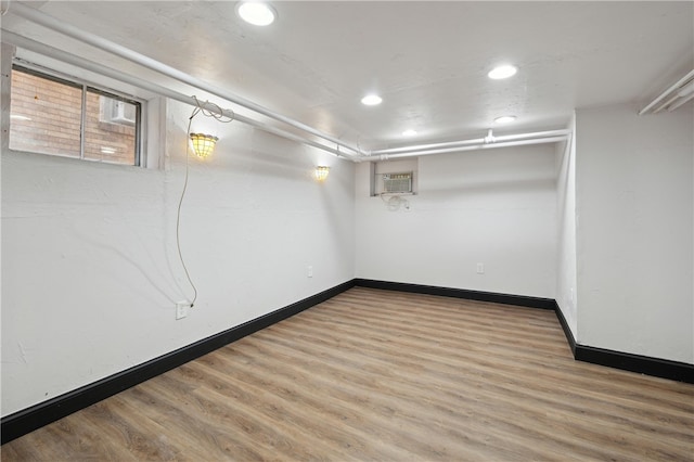 basement featuring hardwood / wood-style floors and an AC wall unit