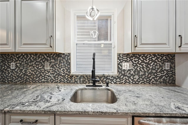 kitchen with sink, decorative backsplash, light stone countertops, and hanging light fixtures