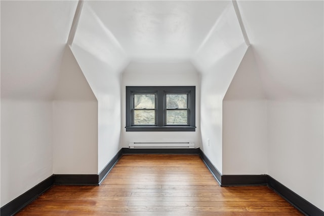 additional living space featuring a baseboard radiator, lofted ceiling, and hardwood / wood-style floors