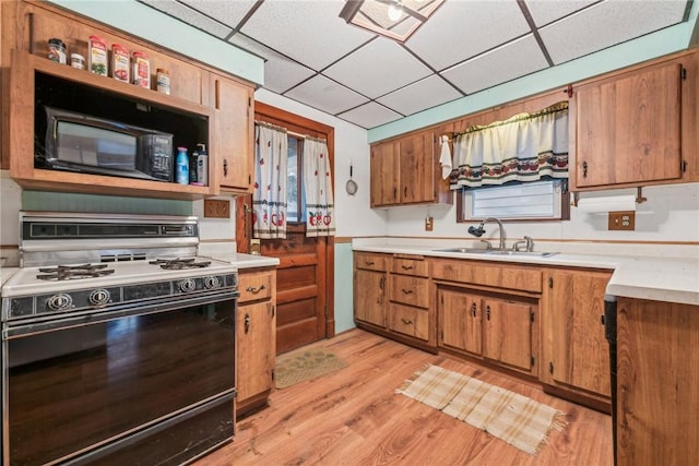 kitchen featuring a drop ceiling, sink, range with gas cooktop, and light hardwood / wood-style flooring