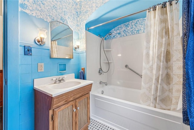 bathroom with vanity, shower / bathtub combination with curtain, and tile walls