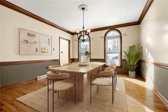 dining area featuring an inviting chandelier, crown molding, and light hardwood / wood-style flooring