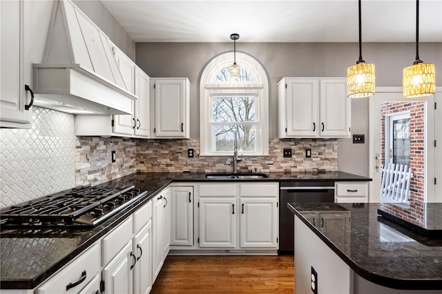 kitchen featuring white cabinetry, premium range hood, decorative light fixtures, and dishwashing machine