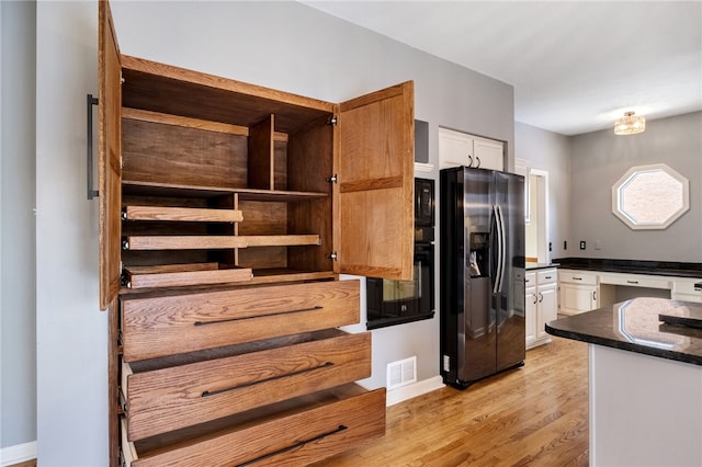 kitchen featuring white cabinetry, stainless steel fridge, light hardwood / wood-style flooring, and black microwave