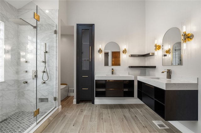 bathroom featuring a high ceiling, vanity, toilet, and a shower with shower door