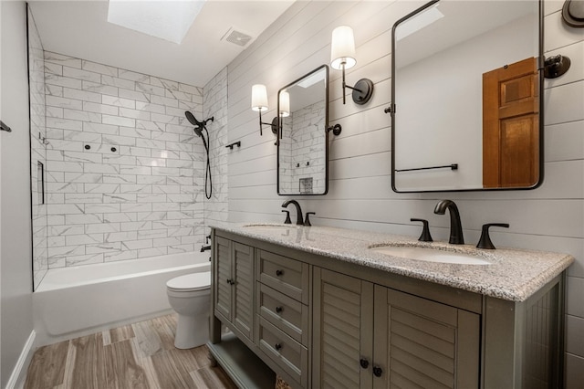 full bathroom featuring vanity, tiled shower / bath, hardwood / wood-style flooring, and toilet