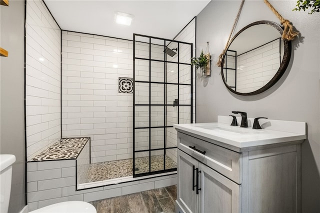 bathroom featuring vanity, a tile shower, and toilet