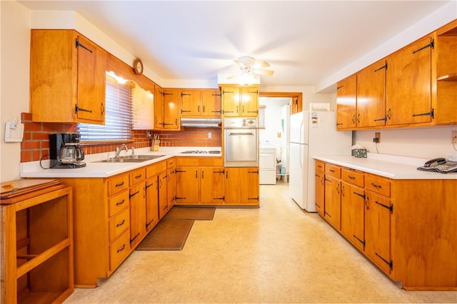 kitchen with washer / dryer, sink, white appliances, ceiling fan, and decorative backsplash