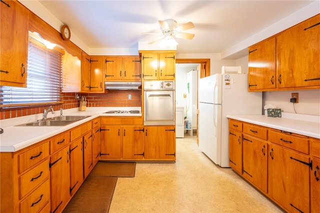 kitchen with sink, white appliances, ceiling fan, tasteful backsplash, and washer / dryer