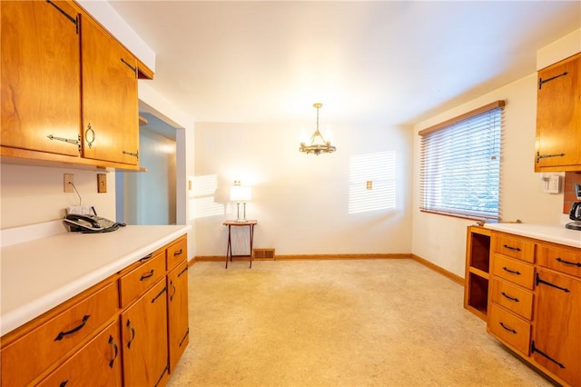 kitchen with light carpet and hanging light fixtures