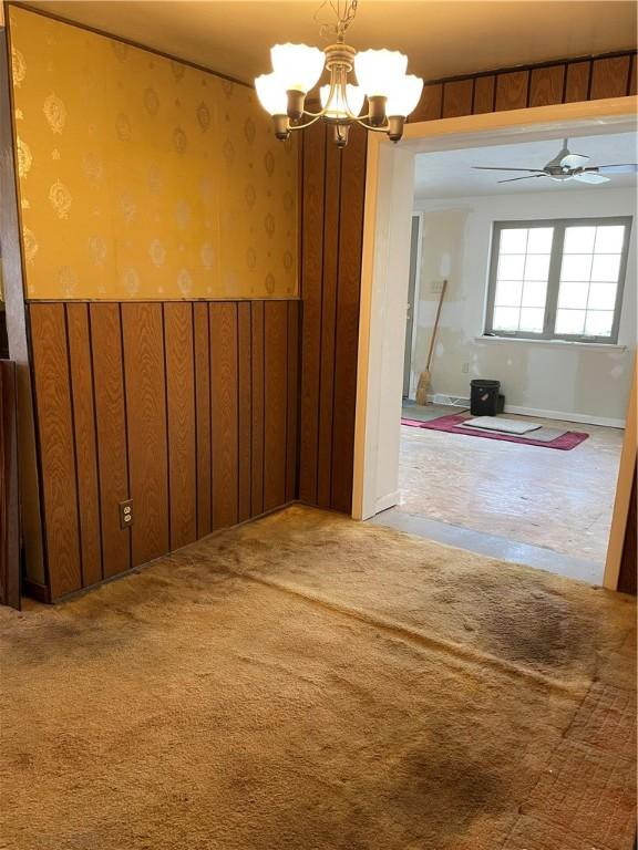 empty room featuring carpet floors and ceiling fan with notable chandelier