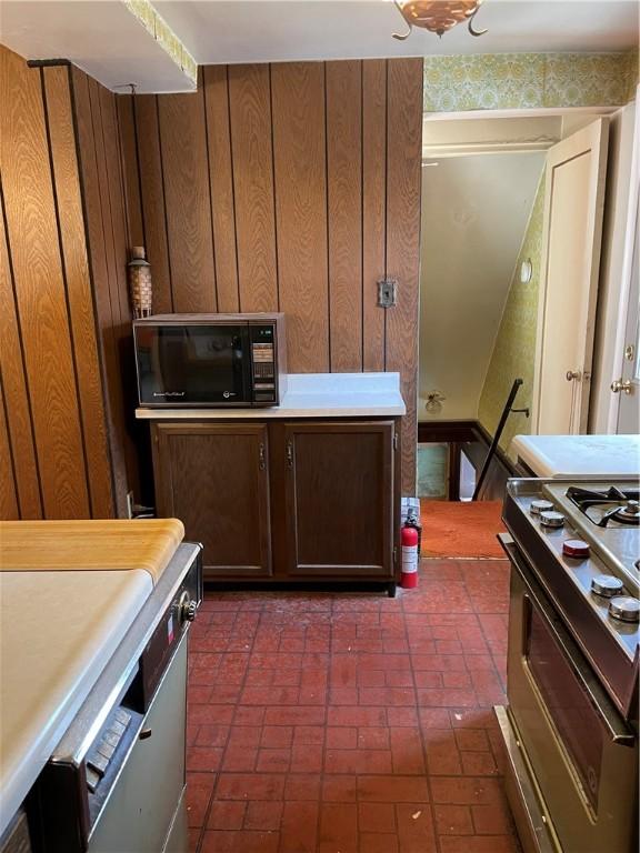 kitchen with gas stove and wood walls