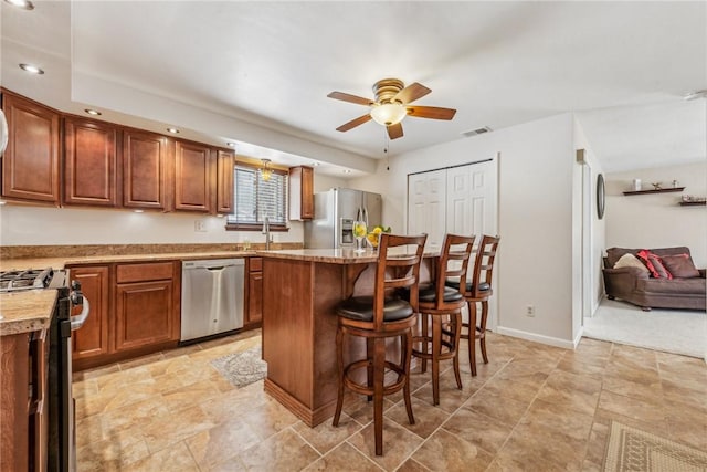 kitchen featuring a kitchen island, sink, a kitchen breakfast bar, ceiling fan, and stainless steel appliances