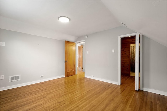 unfurnished room featuring lofted ceiling and light hardwood / wood-style flooring