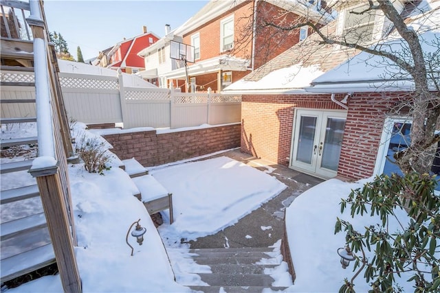 snow covered patio featuring french doors