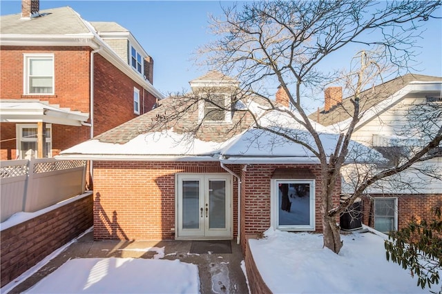 snow covered rear of property featuring french doors