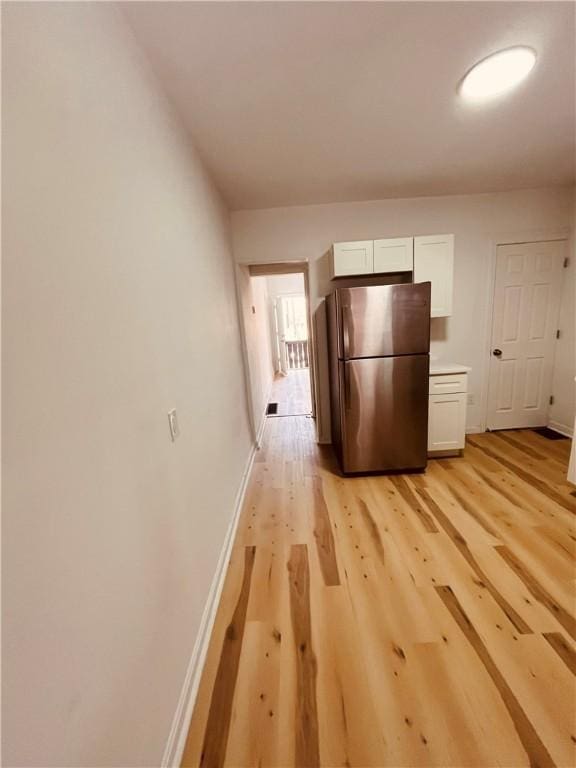 kitchen with white cabinetry, stainless steel refrigerator, and light hardwood / wood-style floors