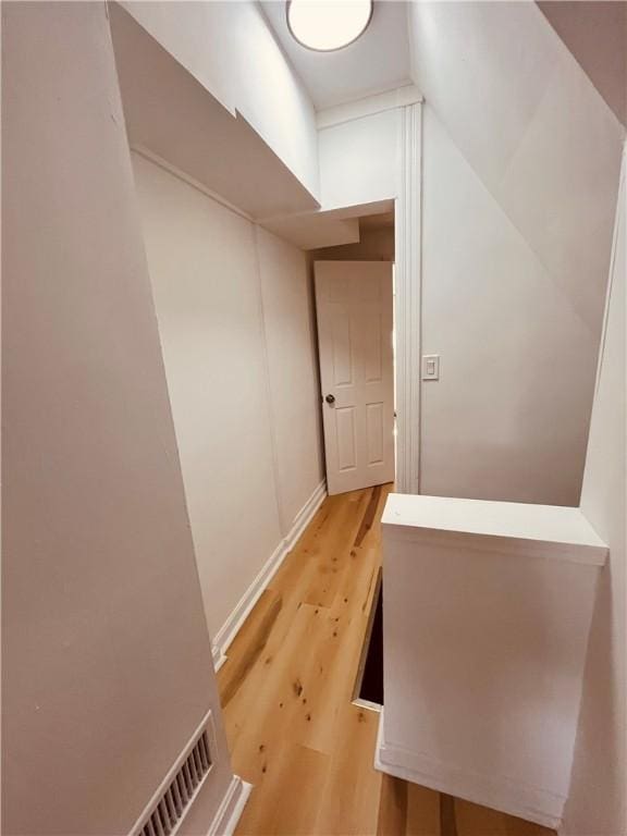 hall with lofted ceiling and light hardwood / wood-style floors