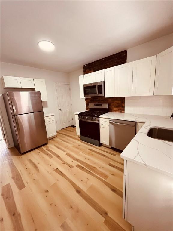 kitchen featuring light wood-type flooring, stainless steel appliances, sink, and white cabinets