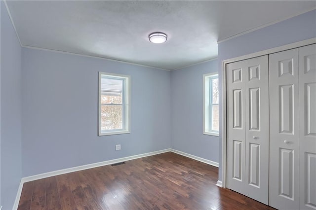 unfurnished bedroom with crown molding, dark hardwood / wood-style flooring, and a closet