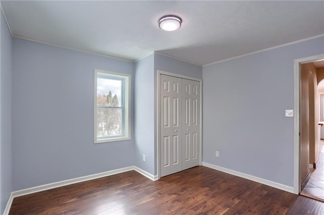 unfurnished bedroom featuring crown molding, dark hardwood / wood-style floors, and a closet