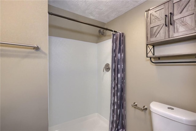 bathroom with toilet, a textured ceiling, and a shower with curtain