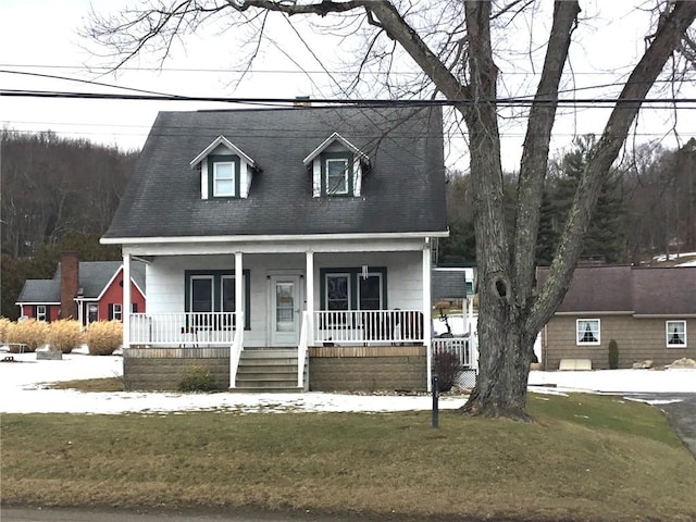 cape cod house featuring a front lawn and covered porch