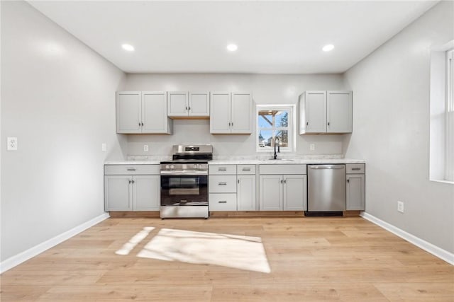 kitchen featuring appliances with stainless steel finishes, sink, gray cabinetry, and light hardwood / wood-style flooring