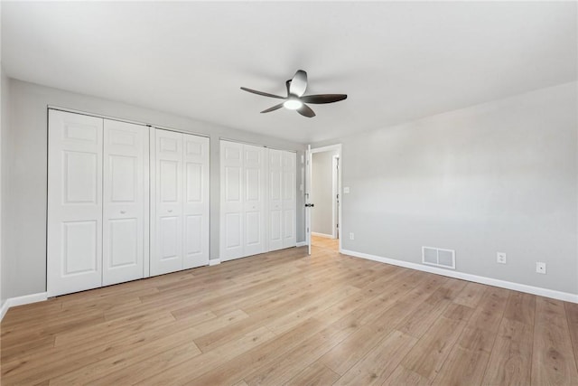 unfurnished bedroom featuring two closets, light hardwood / wood-style flooring, and ceiling fan