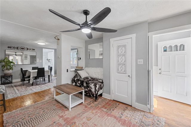 interior space with ceiling fan, a textured ceiling, and light wood-type flooring