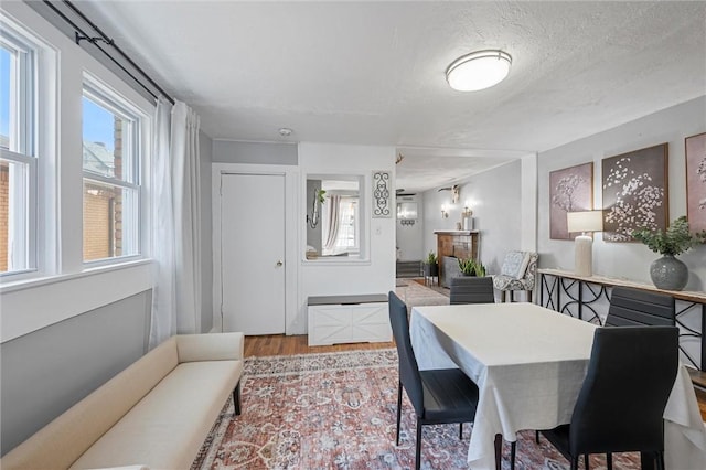 dining room featuring a fireplace, light hardwood / wood-style floors, and a textured ceiling