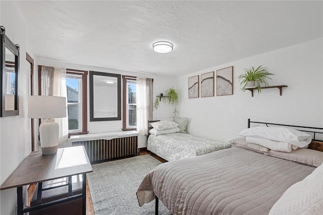 bedroom featuring radiator heating unit, a barn door, and a textured ceiling