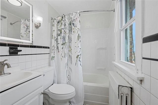 full bathroom featuring shower / bathtub combination with curtain, tile walls, radiator heating unit, vanity, and toilet