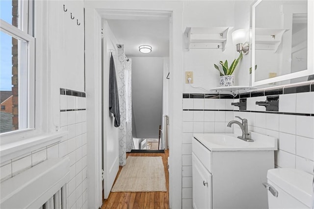 bathroom featuring vanity, toilet, hardwood / wood-style floors, and tile walls