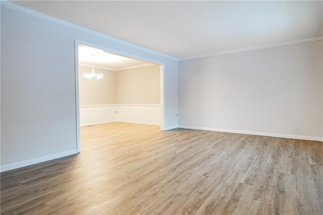 empty room with an inviting chandelier, hardwood / wood-style floors, and crown molding