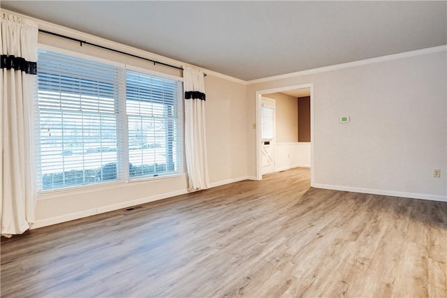 empty room with ornamental molding and light hardwood / wood-style floors