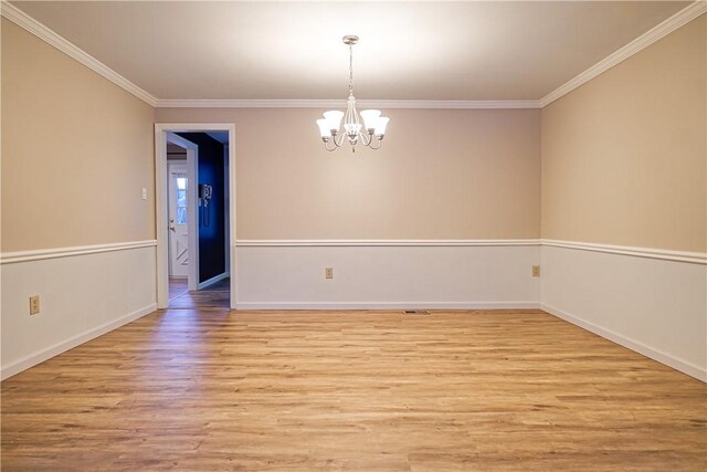 unfurnished room with an inviting chandelier, ornamental molding, and light hardwood / wood-style floors