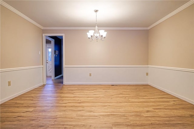 empty room featuring a notable chandelier, ornamental molding, and light wood-type flooring