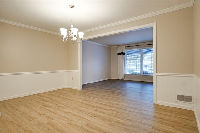 empty room with hardwood / wood-style flooring, crown molding, and a chandelier