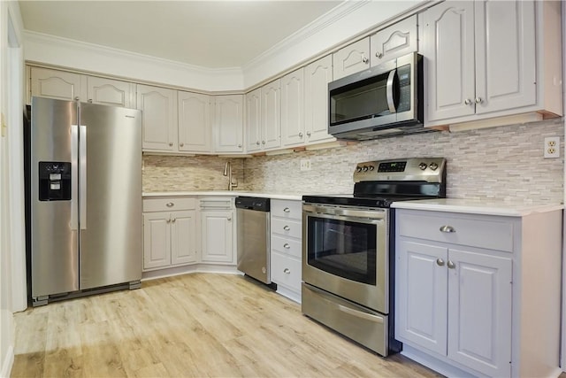 kitchen with crown molding, decorative backsplash, light wood-type flooring, and appliances with stainless steel finishes